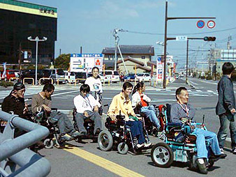 石川さんを先頭に街の視察をするNPO利用者の写真