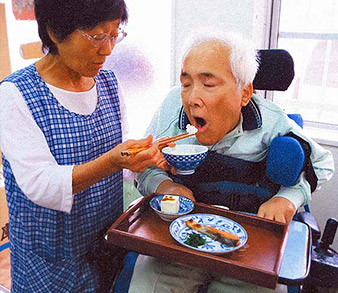 奥様の介助で食事をとる浜野さんの写真