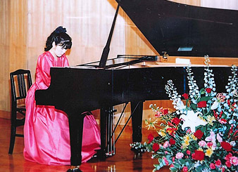 ピアノ演奏をするピンクのドレスを着た清水さんの写真