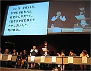 写真:講演会で大スクリーンに映し出される要約筆記
