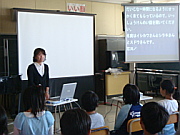 写真：液晶プロジェクターと100インチスクリーンを用いて授業をしている様子