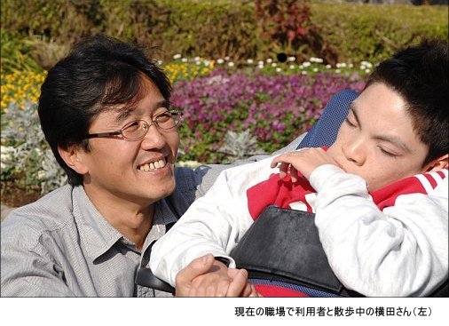 写真:現在の職場で利用者と散歩中の横田さん(左)。優しいまなざしで利用者を見つめる。