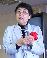 写真:高森さん。白いジャケットに赤いバラ