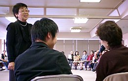 写真:ワークショップ。2人の背中越しに、ほほえむ高森さんが見える