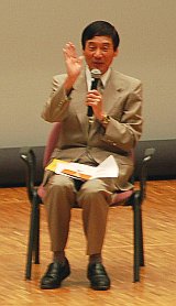 写真:舞台の上の椅子に座って話す講師