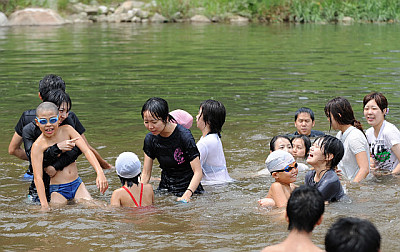 写真：ボランティアの学生たちと一緒に川遊びを楽しむ子どもたち