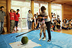 写真：川のそばでやる予定だったスイカ割りは、増水のため屋内で実施