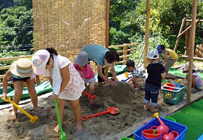 写真:砂場用の遊具で遊ぶ子どもと親