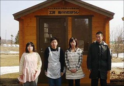 写真:わかば基金で建てたログハウスの前に、のんき村スタッフが並ぶ