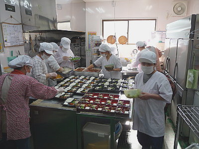 写真：メンバー、職員、ボランティア、みんなでお弁当を作っている様子