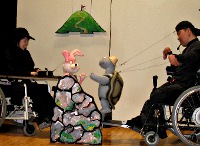写真：車いすを利用している人が人形劇をしている