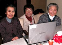 写真：パソコンの前で微笑んでいる利用者たち