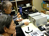 写真：会員がデジタル音声の図書をCDにコピーしている。