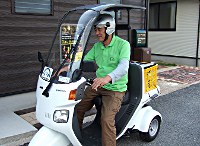 写真:利用者が原付三輪バイクでビールを配達している。