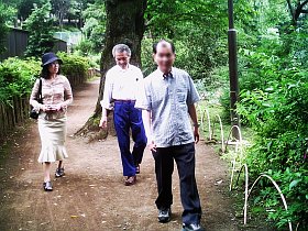 写真：公園の木立の中の道を３人が歩く